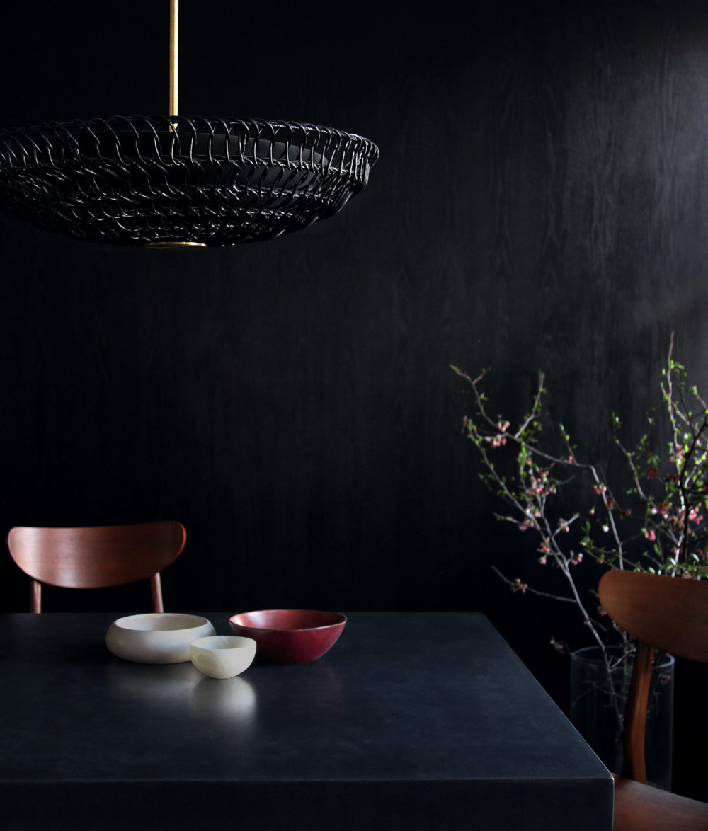 ventila pendant light over a moody dining room table.