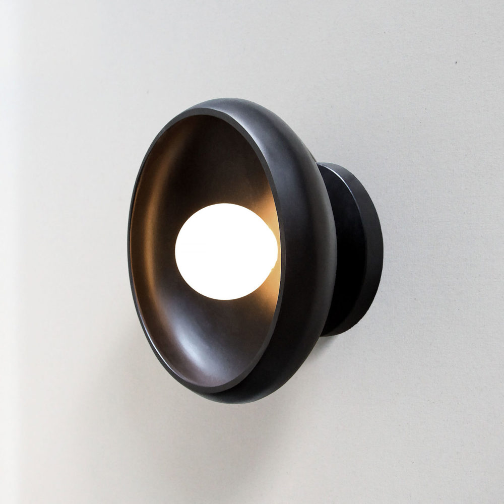 lit modern stone sconce light fixture in black onyx and a tala bulb.
