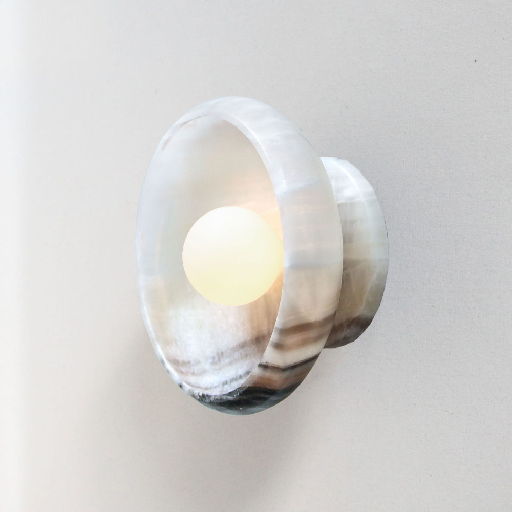 lit modern stone sconce light fixture in black and white onyx and a tala bulb.