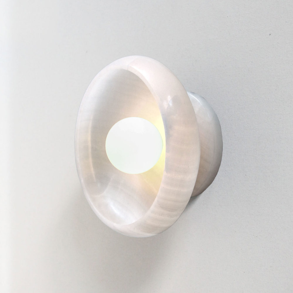 lit modern stone sconce light fixture in milk white onyx and a tala bulb.