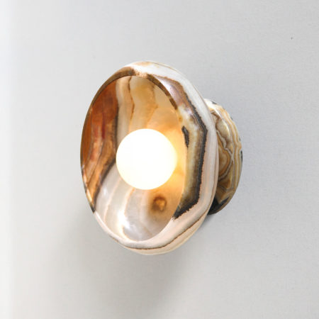 lit modern stone sconce light fixture in terra onyx and a tala bulb.