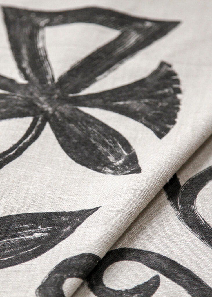 Khovar_Banner_03 This collection draws its inspiration from the tribal villages of Hazaribagh in Northeastern India, where the mud walls of village homes are adorned with expansive, figurative murals. The process begins with a dark earthen base, layered with pale clay. Before the top layer dries, women in the villages brush away the lighter clay using broken combs or their fingers, revealing fluid, organic silhouettes.